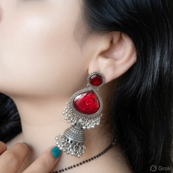 Woman wearing red stone silver jhumka earrings with intricate oxidised silver detailing