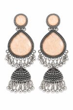 Woman wearing light peach stone silver jhumka earrings with intricate oxidised silver detailing